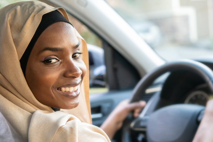 Smiling black muslim woman driving her vehicle